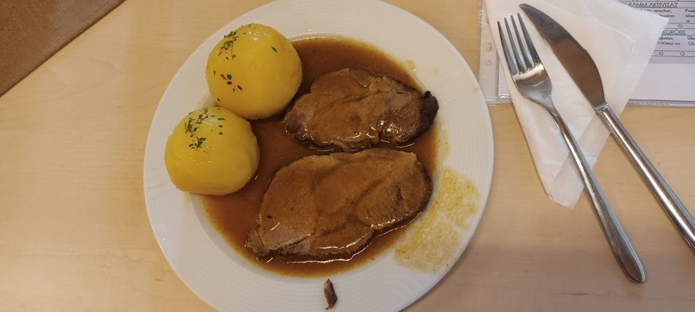 Mittagessen: Fleisch in Saft und zwei Knödel auf Teller.