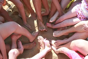 Viele Füße bilden einen Kreis im Sand